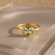 a gold green amethyst ring shown on beige background. green gemstone, green birthstone, february birthstone, february gemstone, stack set, stacking rings, gemstone ring, birthstone ring, mother's day gift for her, gift for mom, gift for fiance, gift for girlfriend, wedding jewelry, bridesmaid jewelry, anniversary jewelry, anniversary gift, birthday gift, christmas gift, valentine's day gift, valentine's day rings, dainty ring, cocktail ring, statement ring, bezel set