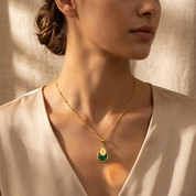 Woman wearing a personalized Green Onyx May birthstone and engraved name necklace in yellow gold.
