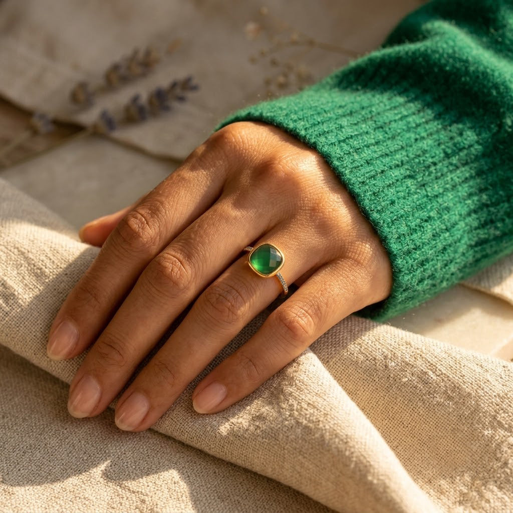 Green onyx cushion ring worn with a green sweater in a naturally lit lifestyle photograph.