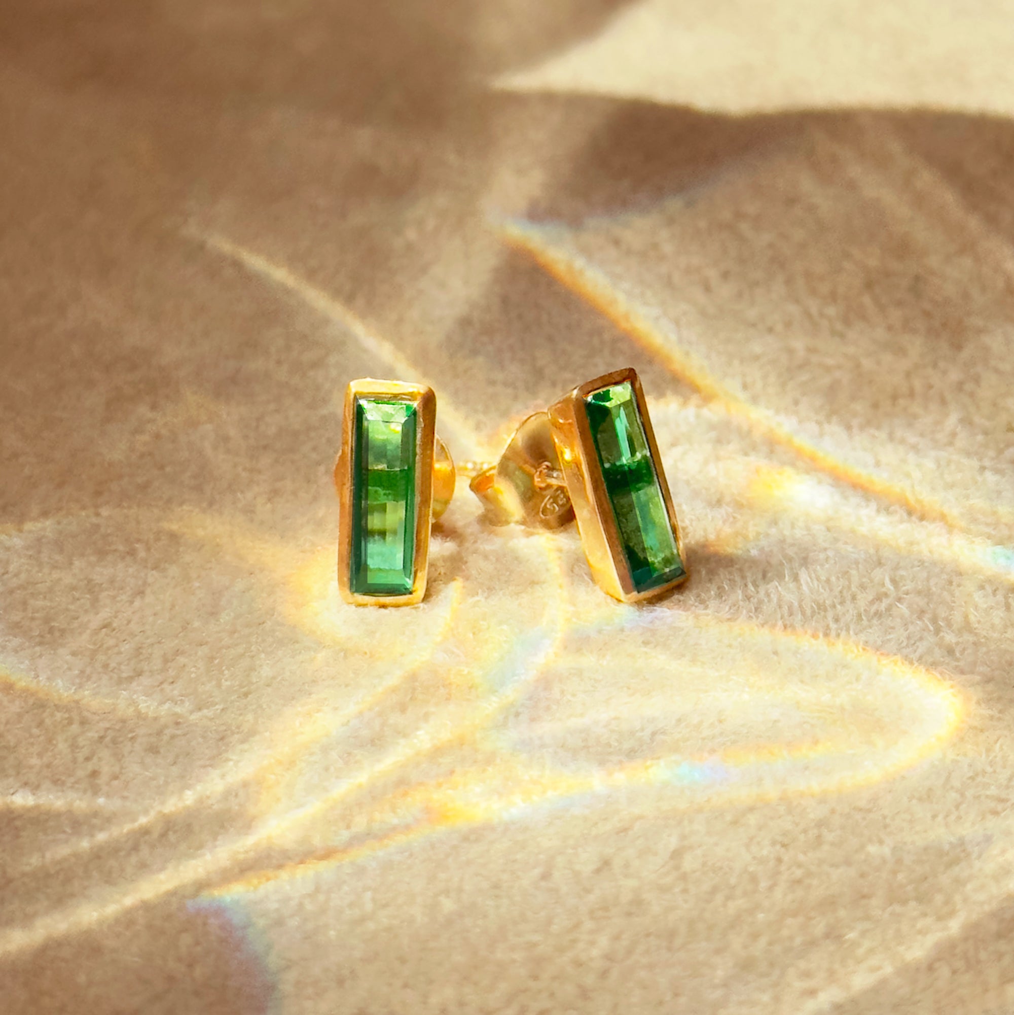 Green Emerald baguette birthstone stud earrings on beige background