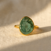 Rough-cut green tourmaline teardrop ring in yellow gold vermeil displayed on warm beige linen.