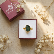 Green tourmaline ring presented in an open burgundy Danique Jewelry gift box with dried flowers.