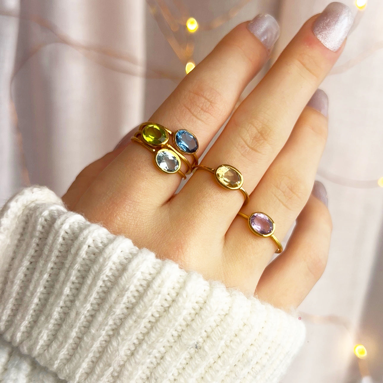 Model stylishly stacking the small oval ring collection. stack set, stacking rings, gemstone ring, Dainty oval birthstone stacking rings shown on hand featuring amethyst for February, aquamarine for March, peridot for August, and citrine for November. Customizable family birthstone jewelry gift for moms, grandmothers, or daughters.