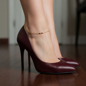 Model adjusting a dainty gold birthstone anklet, personalized ankle bracelet for moms, sisters, bridesmaids, or everyday wear.