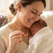 Mother holding her baby while wearing a custom family birthstone necklace with three stacked baguette gemstone charms.
