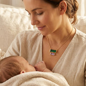 New mom wearing a custom birthstone necklace while holding her baby, featuring stacked baguette stones for mom and kids.