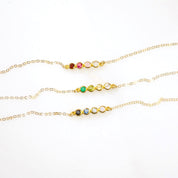 Three necklaces each with a four stone bar dainty birthstone necklace featuring garnet, ruby, pink chalcedony and aqua chalcedony. One featuring green onyx, peridot, citrine and clear. One featuring black onyx, kyanite, blue topaz and moonstone on white background