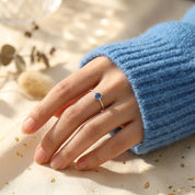 Hand modeling delicate kyanite ring in gold, dainty September birthstone ring with sapphire blue gemstone