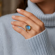 Gold rough cut labradorite statement ring worn on woman's hand with blue and green gemstone flash