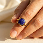 Woman wearing lapis lazuli bezel ring in gold, bold cushion cut gemstone ring styled as modern statement jewelry