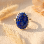 Close-up of faceted oval blue lapis lazuli gemstone ring in a smooth sterling silverbezel setting