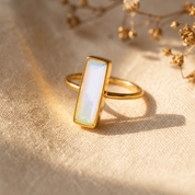 Large Opalite bar ring in yellow gold with iridescent rectangular October birthstone gemstone.
