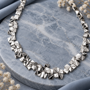 Silver geometric pyramid statement necklace with faceted metallic elements on gray stone
