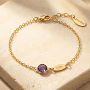 Custom birthstone name bracelet with one purple birthstone and engraved Katy name charm on gold chain.