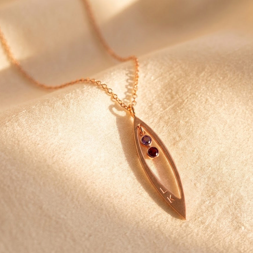 Close-up of marquise pendant necklace with tiny faceted birthstones, minimalist family jewelry in rose gold vermeil