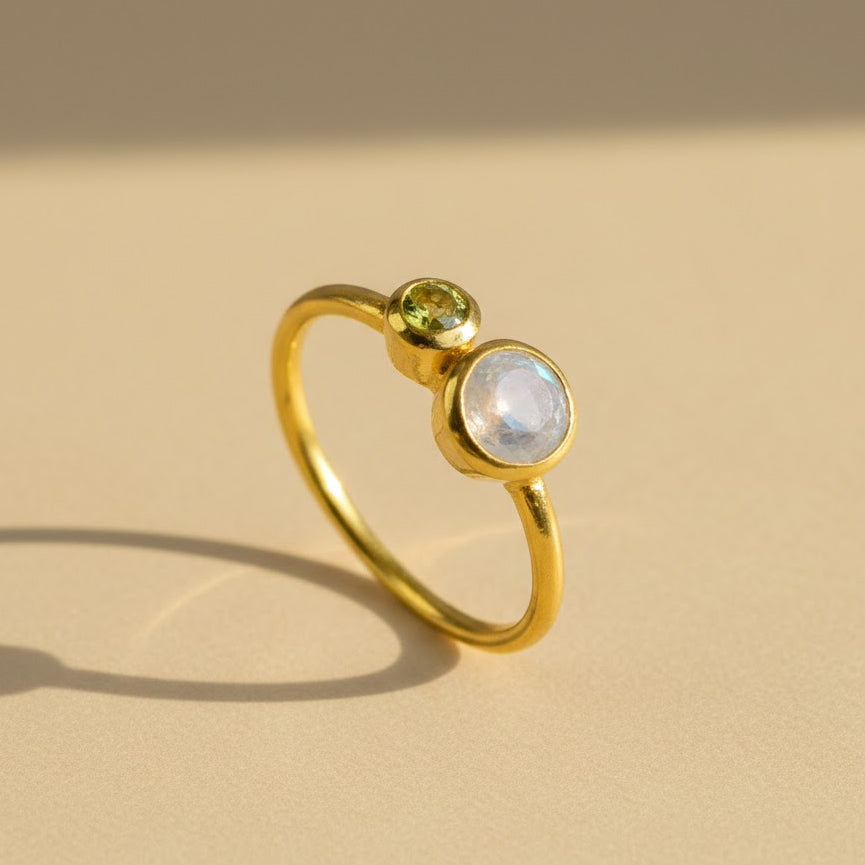 One mothers duel bezel set ring in gold filled featuring a 5mm moonstone and 3mm peridot birthstones on white background.