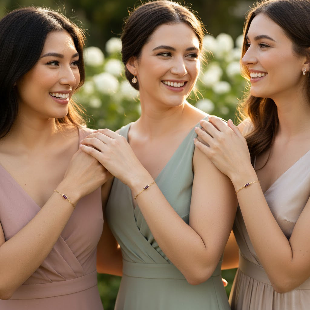 Three women wearing matching minimalist gold birthstone bracelets, personalized rectangular gemstone bar bracelets for bridesmaids, sisters or best friends, custom engraved dainty jewelry gift for wedding party, bridal shower, birthday or meaningful friendship keepsake.