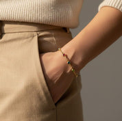 Mom wearing a custom birthstone bracelet on her wrist featuring tiny bezel-set natural gemstones on a delicate gold chain. Personalized family birthstone bracelet designed to represent children or grandchildren, handcrafted in sterling silver or gold vermeil. Minimalist everyday jewelry gift for mom, mama, or grandma, perfect for Mother’s Day, birthday, anniversary, or meaningful family keepsake.