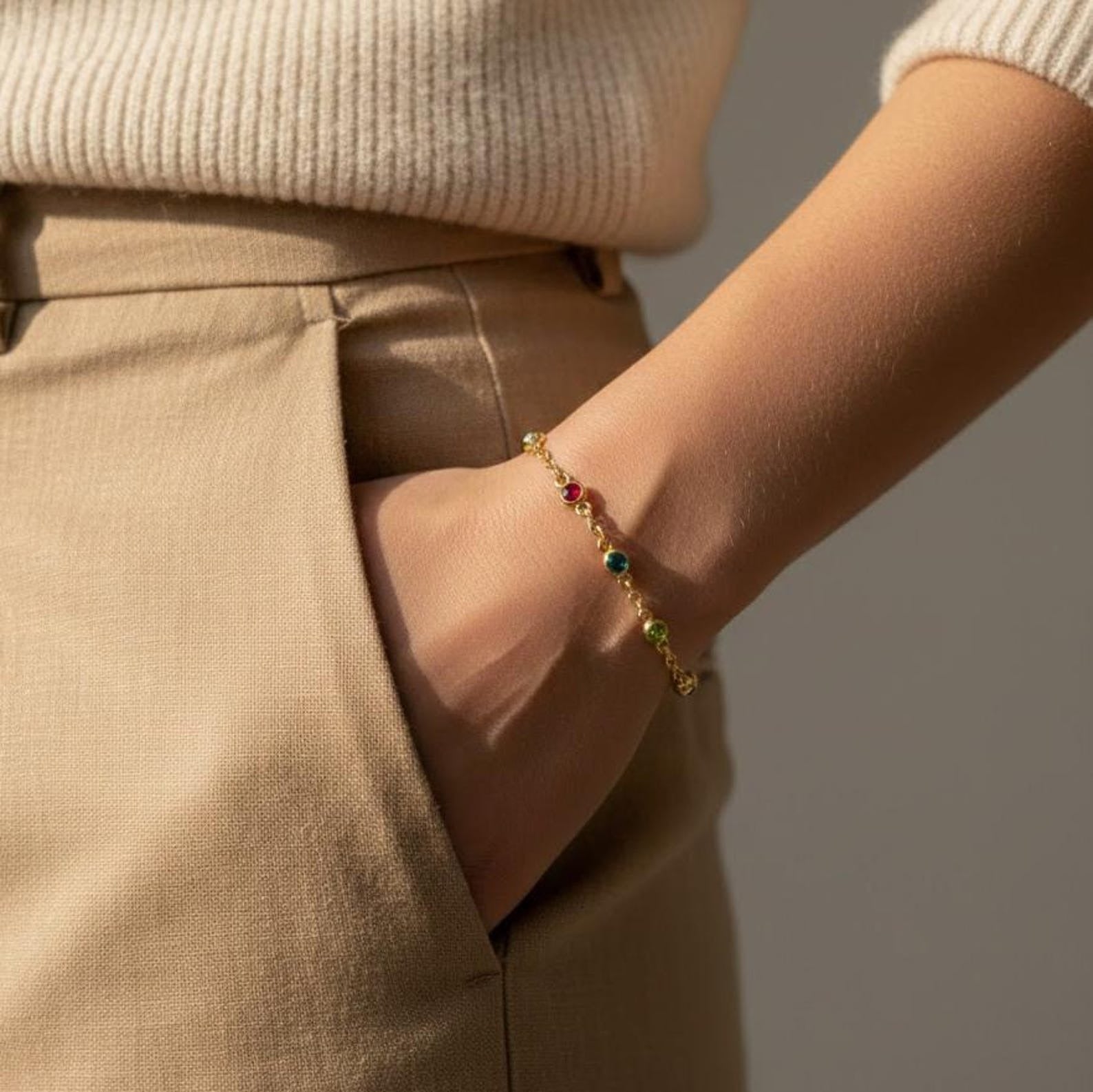 Mom wearing a custom birthstone bracelet on her wrist featuring tiny bezel-set natural gemstones on a delicate gold chain. Personalized family birthstone bracelet designed to represent children or grandchildren, handcrafted in sterling silver or gold vermeil. Minimalist everyday jewelry gift for mom, mama, or grandma, perfect for Mother’s Day, birthday, anniversary, or meaningful family keepsake.