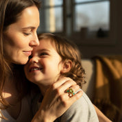 Lifestyle photo of mom and child highlighting meaningful family jewelry, personalized stacking birthstone ring set for mom with kids birthstones, mothers ring set and grandma ring gift, dainty minimalist stackable rings made to order, large oval stone represents mom and small round stones represent children, customize birth months like August peridot and September sapphire for a sentimental keepsake gift for Mother’s Day