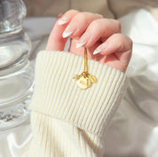 Model holding the Gold disc and custom name tag necklace. Elegant and timeless, personalized Mother's necklace features a round disc with your name, oval tags for your kids and a freshwater pearl charm. Mom necklace, kids names, pearl charm.