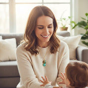 Smiling mom wearing a gold filled custom birthstone cluster necklace while playing with her baby, showcasing four teal and aqua gemstones as a meaningful family necklace, perfect personalized gift for mom or grandma for Mother’s Day or birthday.
