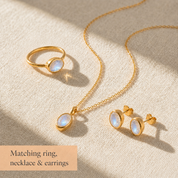 Matching moonstone ring, necklace, and earrings set in yellow gold with soft blue flashes.