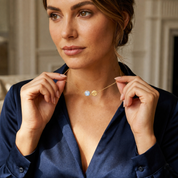 Woman wearing a delicate moonstone initial necklace with a navy outfit for an elegant everyday look.