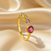 Custom birthstone ring for mom of three kids featuring one large 5mm bezel-set center stone and three 3mm child birthstones on an adjustable gold band, displayed on soft satin fabric. Personalized family jewelry designed for moms who want a meaningful keepsake. Perfect Mother’s Day gift, Christmas gift, or birthday gift for a mom of three, handcrafted in gold vermeil with sparkling multi-stone arrangement celebrating her children.