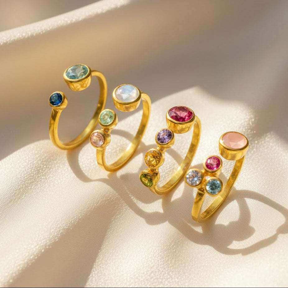 Collection of multi birthstone rings for moms displayed together, each featuring one large bezel-set mother stone paired with two small child birthstones on an adjustable open band. Perfect customizable family jewelry for moms of two kids, ideal for gifting on birthdays, Mother’s Day, Christmas, weddings, or as bridesmaid jewelry. These dainty personalized rings highlight meaningful gemstones in gold vermeil handcrafted settings she’ll treasure.
