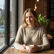 Model wearing dainty multi birthstone necklace while sitting by a window.