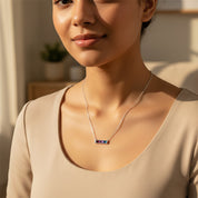 Model wearing dainty multi birthstone necklace while sitting by a window.