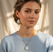 Model wearing an opalite teardrop necklace and matching earrings in a soft blue sweater.