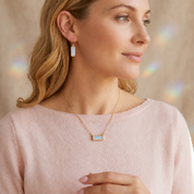 Woman wearing a horizontal Opalite gemstone bar necklace in yellow gold as a minimalist everyday necklace.
