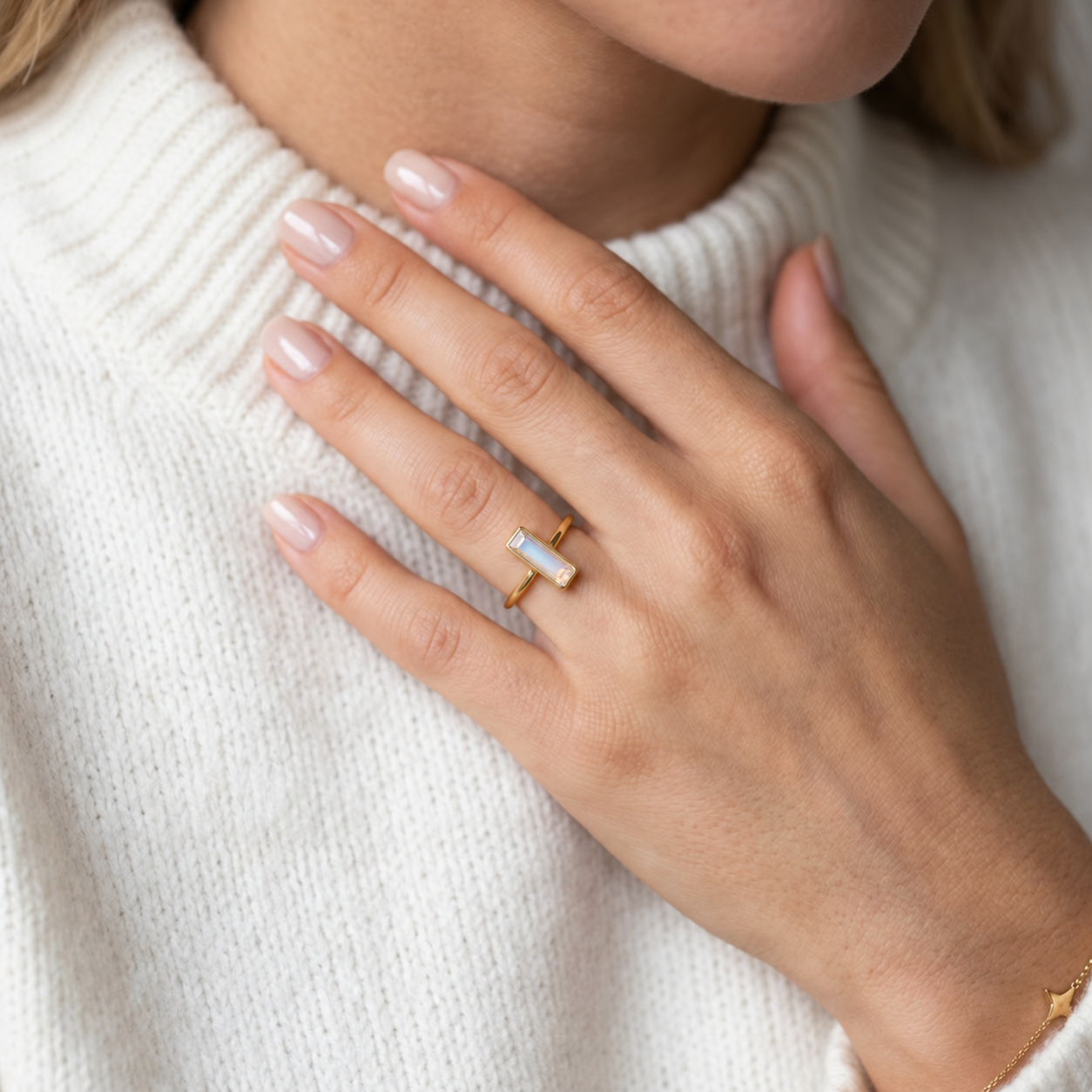 Woman wearing a tiny Opalite baguette ring in yellow gold as a minimalist October birthstone ring.
