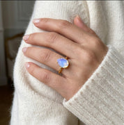 Model wearing an opalite teardrop birthstone ring, a dainty October gemstone ring for women in a delicate prong setting.