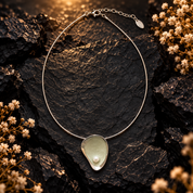 Sage Mist pearl teardrop pendant necklace displayed on dark textured stone
