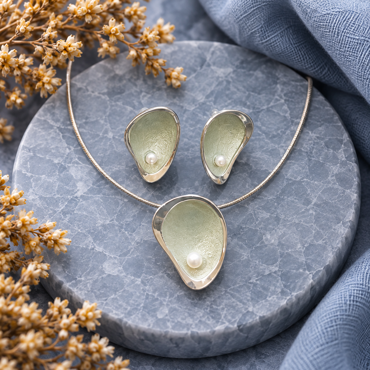 Sage Mist pearl teardrop necklace and matching earrings displayed on gray stone

