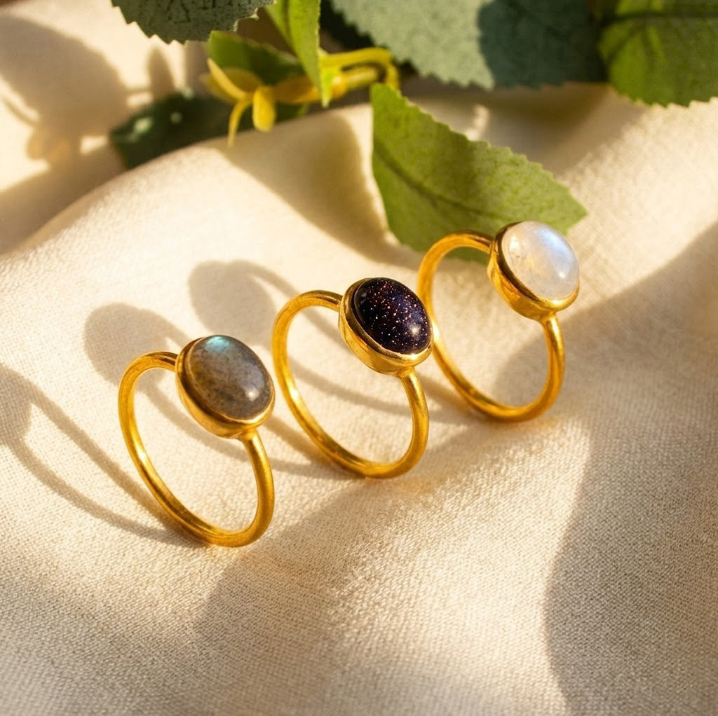 Cabochon gemstone rings in yellow gold shown outdoors with colorful oval stones