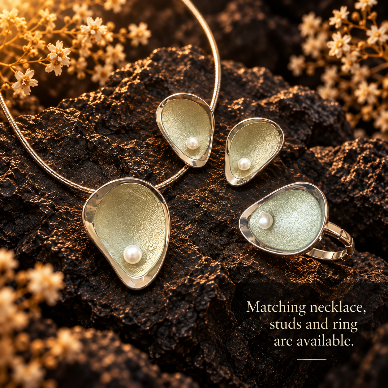 1. Matching sage green sculptural necklace earrings and adjustable ring with pearl accents displayed on dark stone
