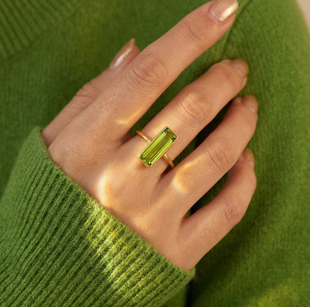 Model wearing a bright green Peridot Quartz bar ring with a coordinating green sweater