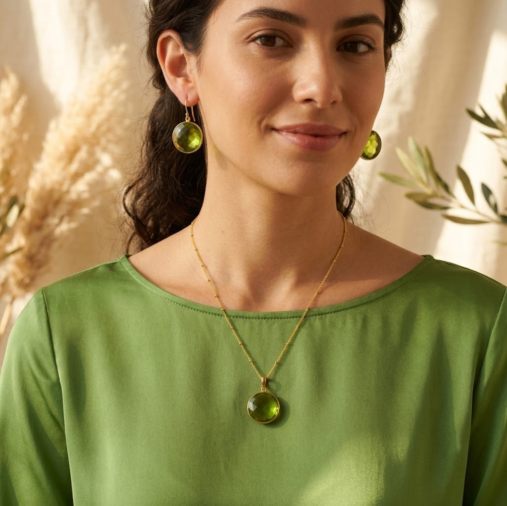 Model wearing a peridot birthstone necklace with a soft green top in natural sunlight.