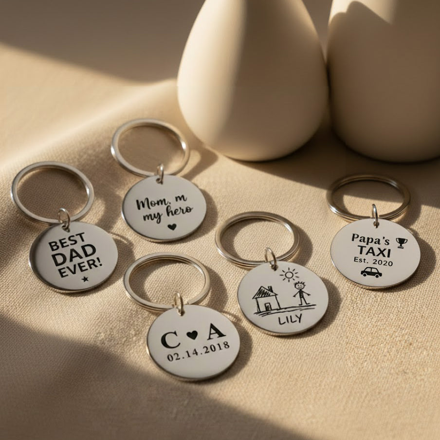 Custom engraved circle keychains displayed on neutral surface, featuring personalized names, dates, and short messages. Polished stainless steel round keychains designed as meaningful keepsakes for dads, moms, and family members. Personalized engraved keychain gifts perfect for Father’s Day, Mother’s Day, birthdays, anniversaries, or everyday reminders of love.