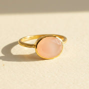 Oval pink chalcedony ring in gold bezel setting featuring soft blush gemstone, dainty oval pink stone ring for women, minimalist stacking birthstone style jewelry in yellow gold vermeil