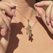 Custom initial birthstone mom necklace shown in motion, delicate gold chain holding a cluster of pastel teardrop birthstone charms with tiny engraved initial leaves, catching warm sunlight at the neckline. Personalized family birthstone jewelry for mom or grandma, perfect for celebrating children or grandchildren, a meaningful Mother’s Day, birthday or new mom gift, minimalist layered necklace style for everyday wear.