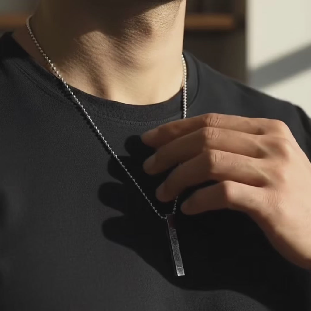 video showcasing Engraved 3D bar necklace for men in stainless steel shown up-close while being held, highlighting deep custom engraving, sleek vertical bar shape, and personalized text options like coordinates, name or Roman numerals. Masculine everyday accessory and meaningful custom gift for boyfriend, dad or husband in modern minimalist style.