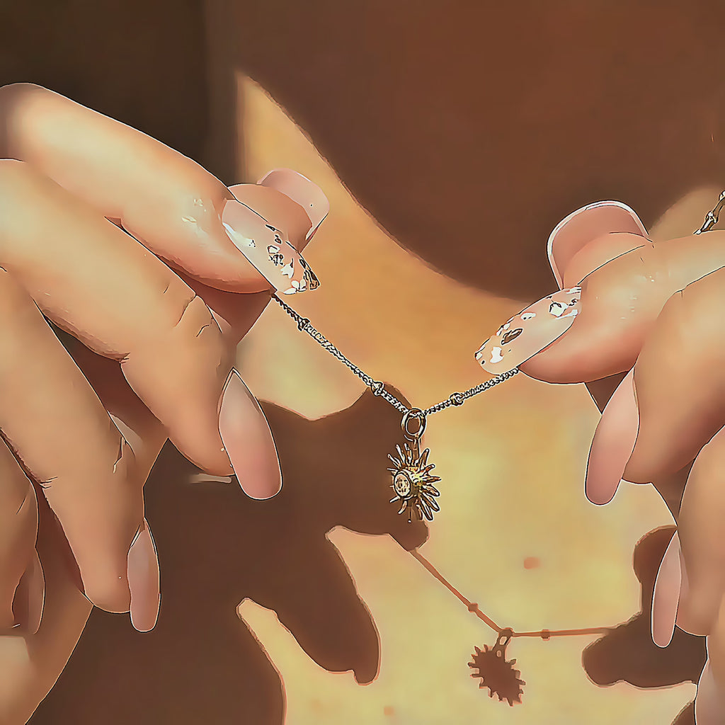 Several custom sunburst birthstone necklaces shown in hand under soft golden light, capturing the shimmer of the satellite chain and the vibrant sparkle of each gemstone. Personalized birthstone jewelry available in gold, silver, and rose gold, a thoughtful birthday, Mother’s Day, Christmas or bridesmaid gift. Modern dainty necklace ideal for layering and everyday wear, with all birthstones offered.