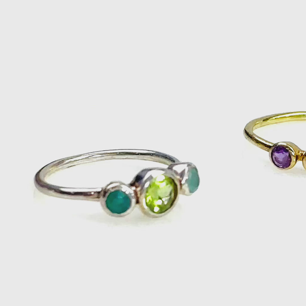 3 custom birthstone rings on a white background. A person wears a ring with one large stone and two small stones on either side on their middle finger. A person wears a two stone ring. A person wears a four stone ring. A person wears  a three stone ring. A person wears a two stone ring. A three stone ring is shown in an open Danique Jewelry box. Gold vermeil, Sterling Silver, Rose gold vermeil, birthstones for every month available, size 5-9, personalized gift for mom christmas, birthday gift, mothers day