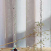 The camera pans down to show a silver and a gold round mother and child pendant necklace. A person wears a gold moonstone necklace with two small stones in pink chalcedony and kyanite quartz. A person shows an up close of the moonstone necklace to show the vibrant blue flash. A silver necklace is in an open Danique Jewelry gift box. This necklace is perfect for christmas gift, mother's day gift, anniversary or birthday present for mom or grandma