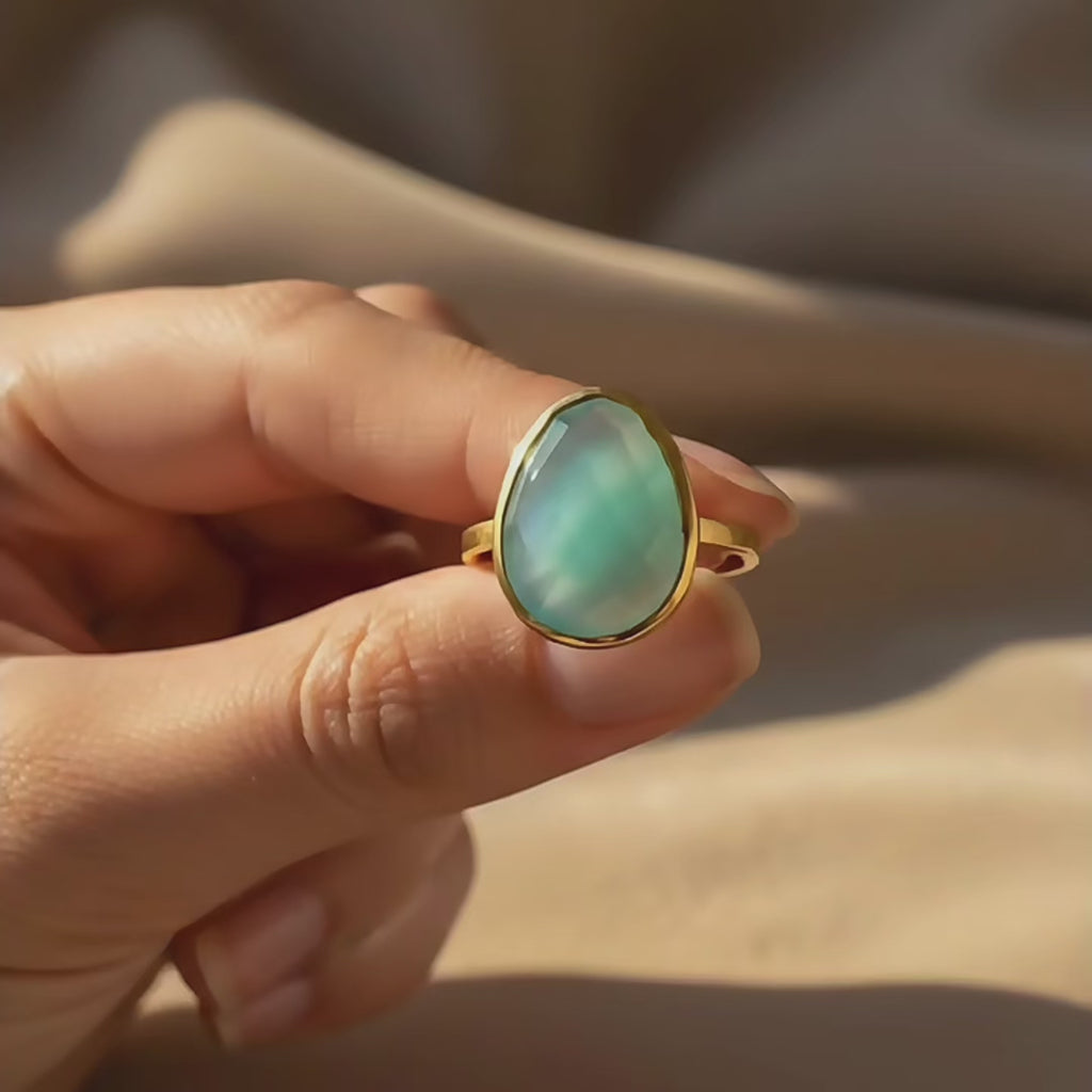 Video showing a pear-shaped aqua chalcedony ring in a gold bezel setting, held in hand in warm natural light to highlight the soft blue gemstone and delicate band.